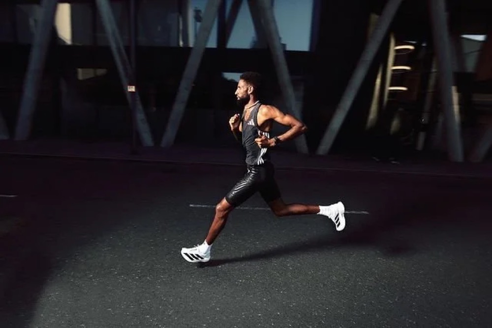 Amanal Petros läuft in adidas-Laufschuhen unter einer Industriekonstruktion