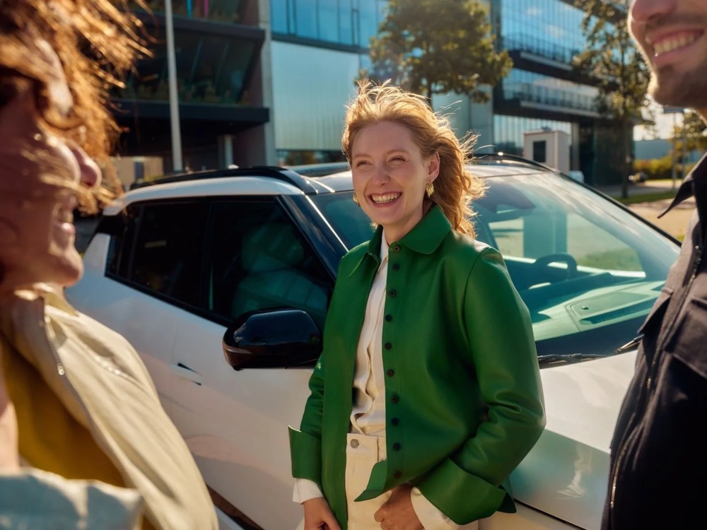 Lächelnde Frau neben ihrem geparkten Dienstwagen, Shooting für Athlon Car Lease in Amsterdam