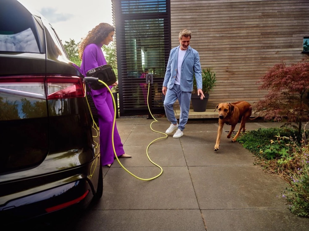 Paar mit Hund neben einem E-Auto, das zu Hause lädt, Shooting für Athlon Car Lease in Amsterdam