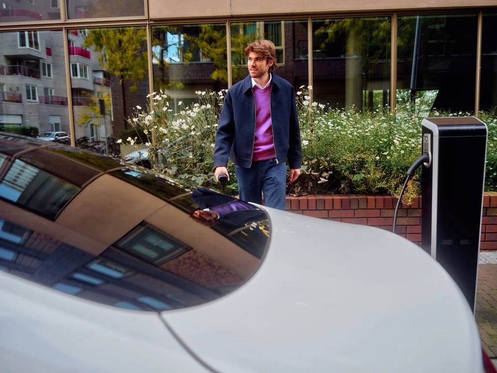 Mann wartet an einer Ladestation neben seinem Auto, Shooting für Athlon Car Lease in Amsterdam
