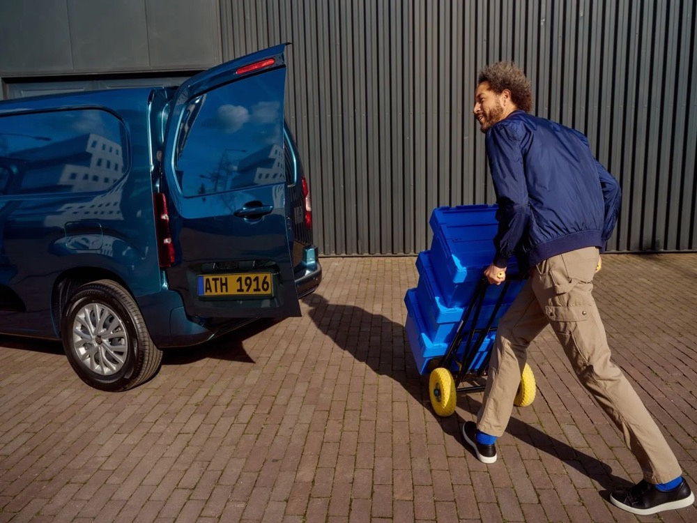 Paketfahrer mit blauen Kisten an seinem Transporter, Shooting für Athlon Car Lease in Amsterdam