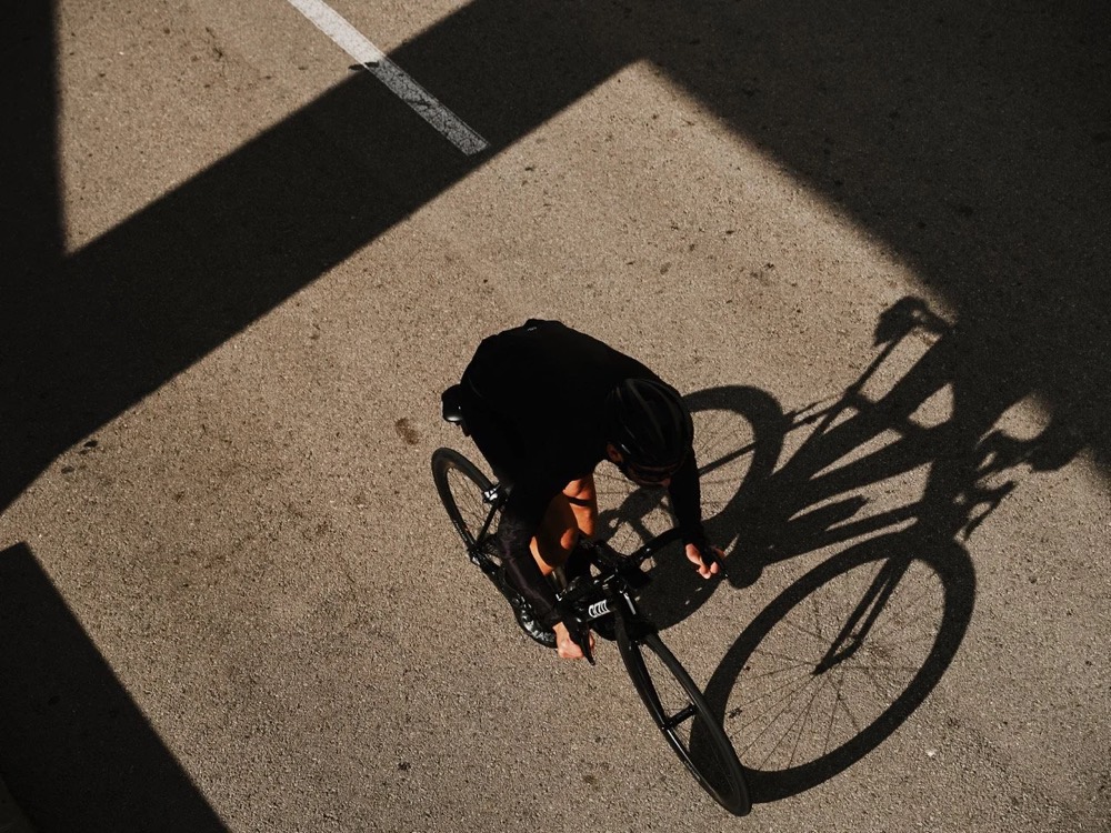 Radfahrer und sein langer Schatten in Barcelona, von oben, DIZO Bikes