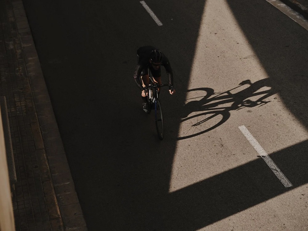 Radfahrer überquert in Barcelona einen Lichtstreifen, von oben, DIZO Bikes