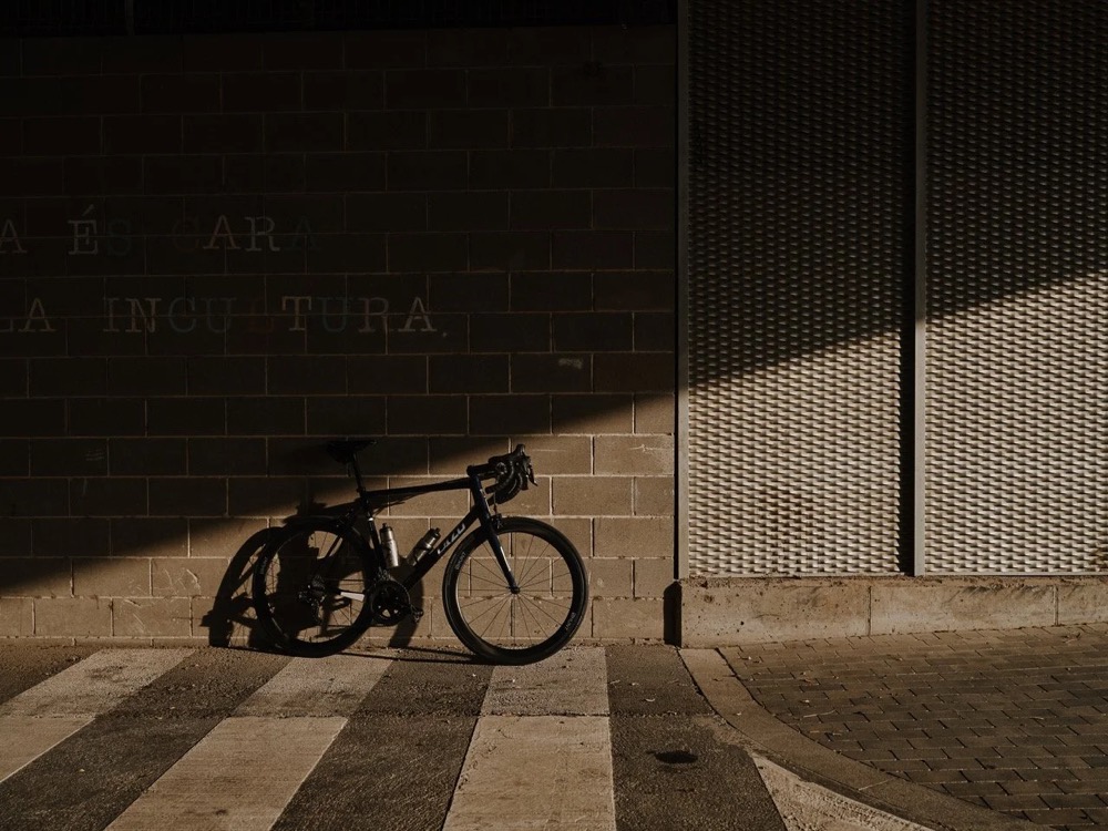 Rennrad lehnt in Barcelona im Schatten an einer Mauer, DIZO Bikes