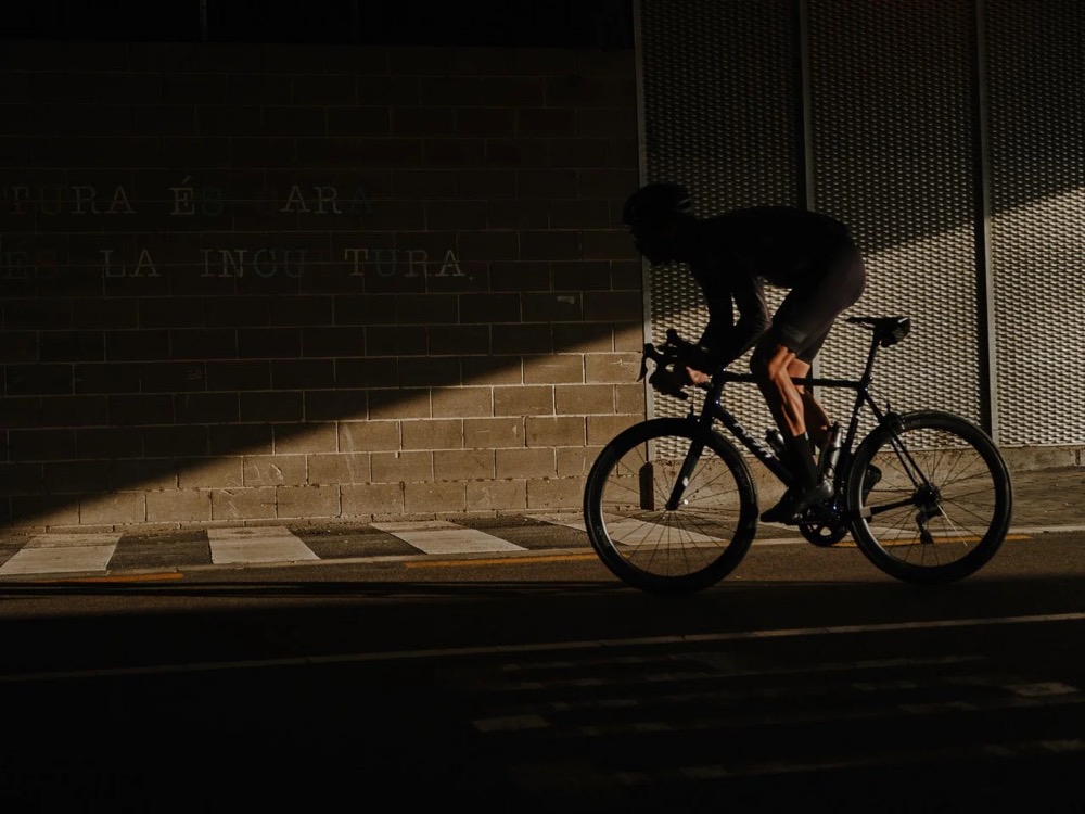 Radfahrer auf dem Rennrad in einem Lichtkegel in Barcelona, DIZO Bikes