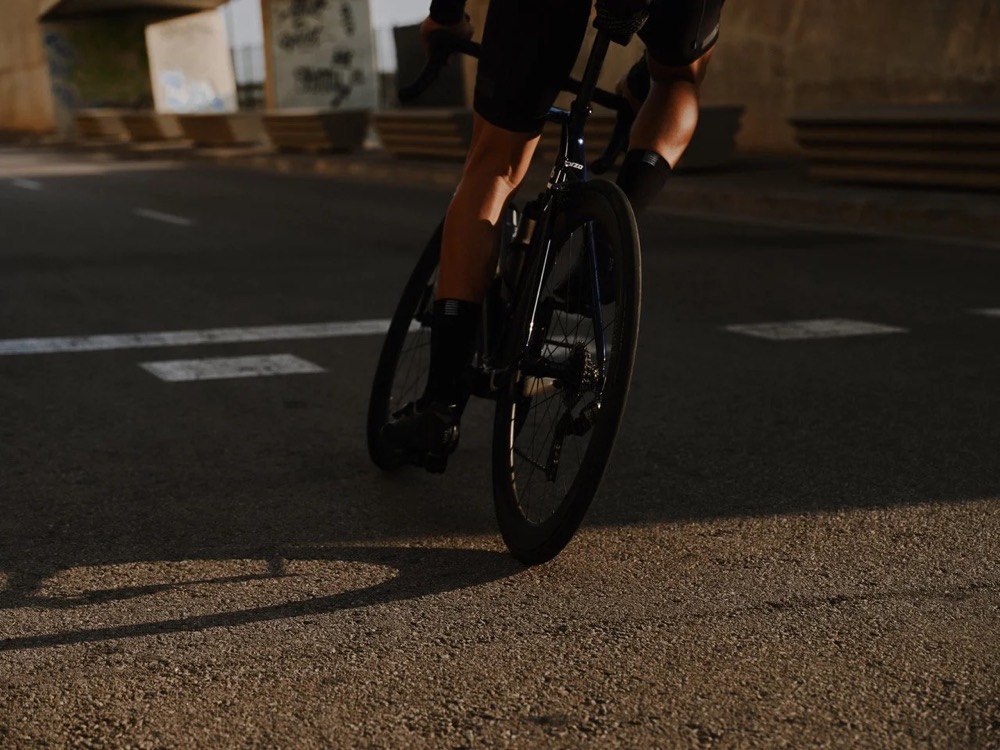 Radfahrer fährt in Barcelona bei tiefer Sonne auf die Kamera zu, DIZO Bikes
