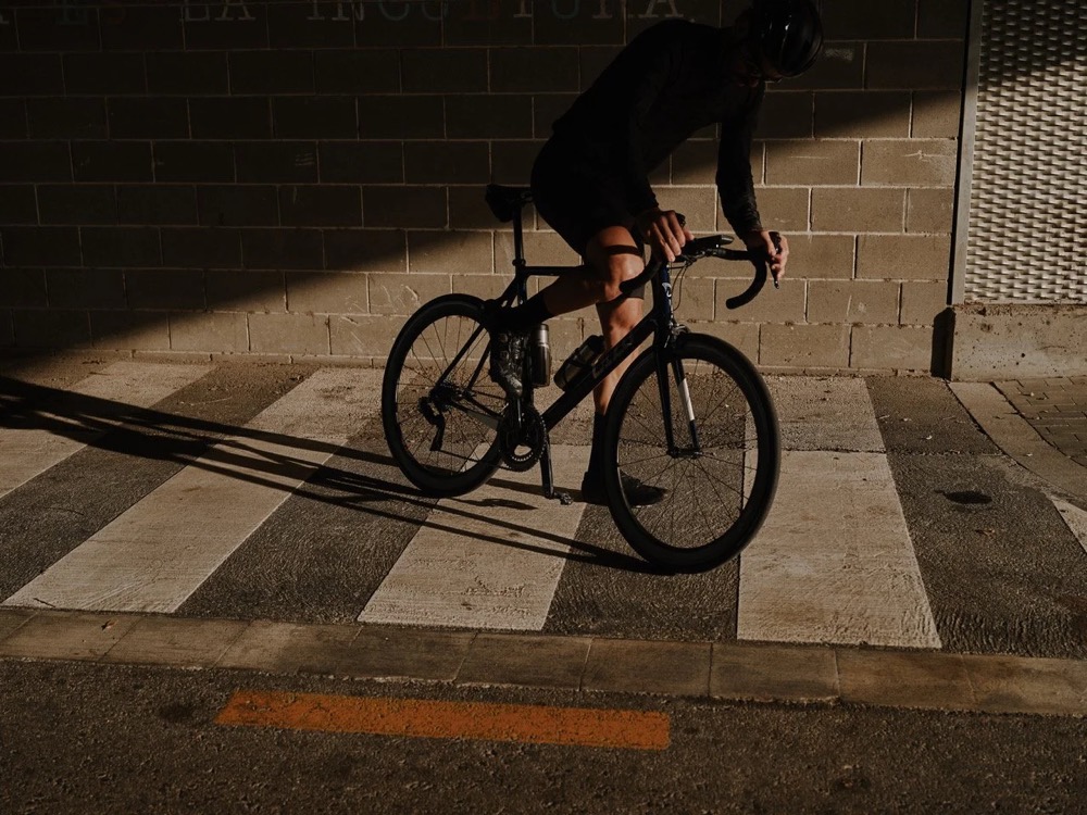 Radfahrer überquert in Barcelona mit dem Rennrad einen Zebrastreifen, DIZO Bikes