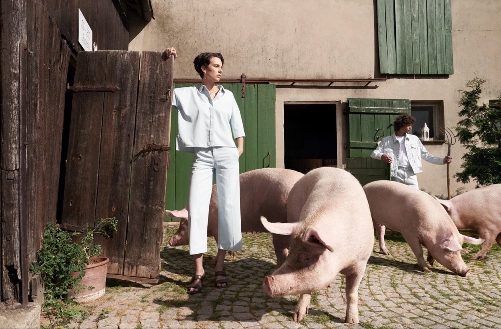 Model in Weiß mit Schweinen auf einem Bauernhof, Drykorn-Kampagne FS/SS 21 auf der SiHo Ranch