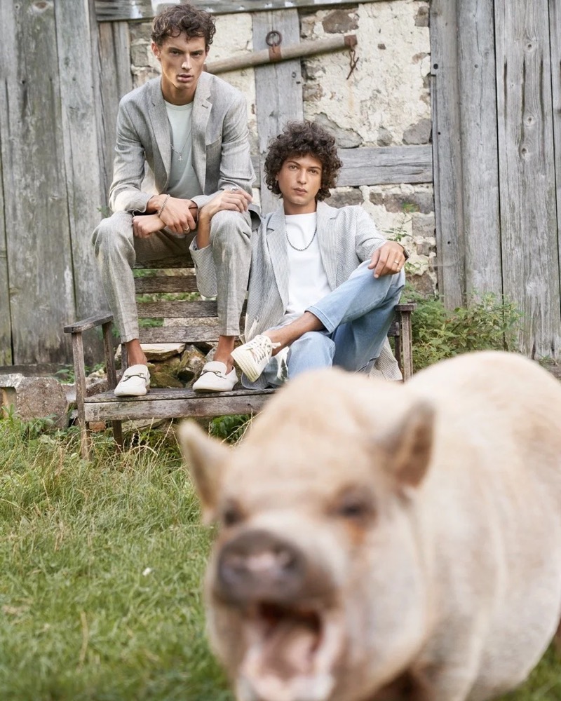 Zwei Models auf einer Bank, im Vordergrund ein Schwein, Drykorn-Kampagne FS/SS 21 auf der SiHo Ranch