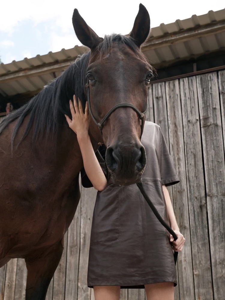 Model mit dem Gesicht an einem dunklen Pferd, Drykorn-Kampagne FS/SS 21 auf der SiHo Ranch