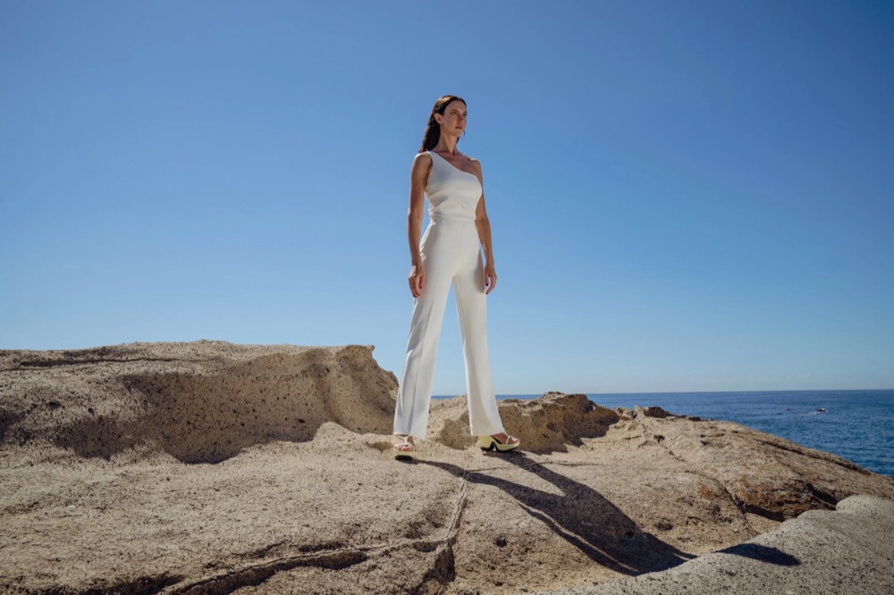 Model in Weiß auf Felsen am Meer, Drykorn-Kampagne FS/SS 23 in Neapel