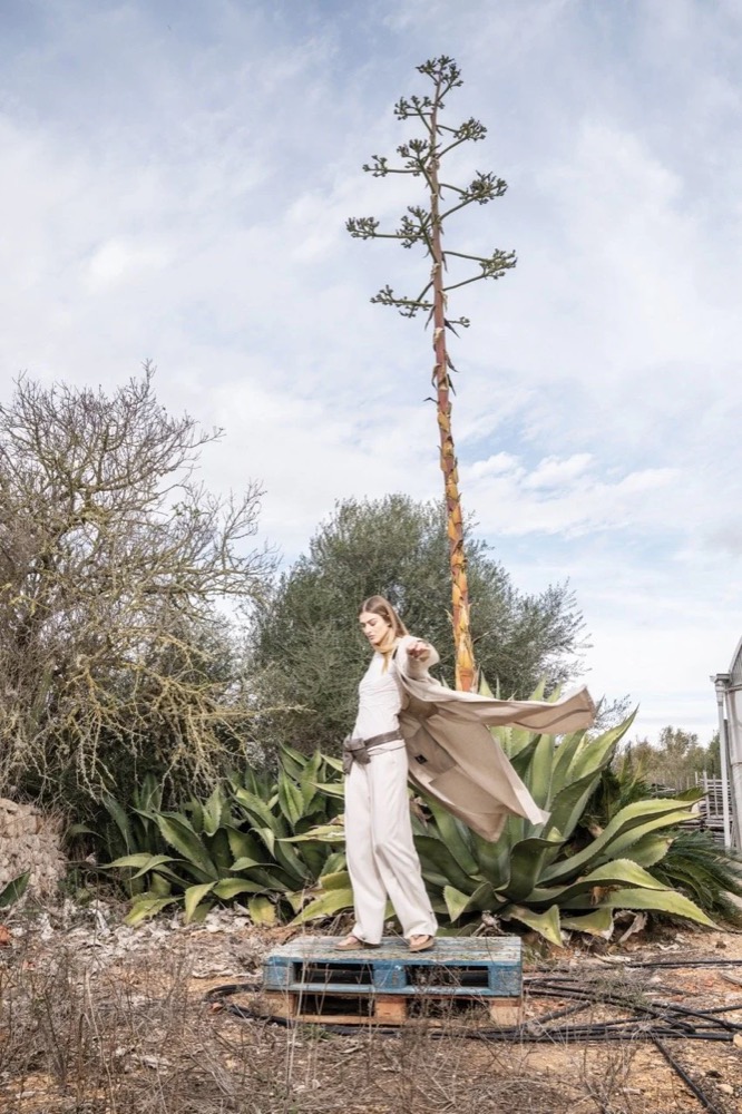 Model unter einer hohen Agavenblüte zwischen Pflanzen, Drykorn-Kampagne FS/SS 24 Teil II auf Mallorca