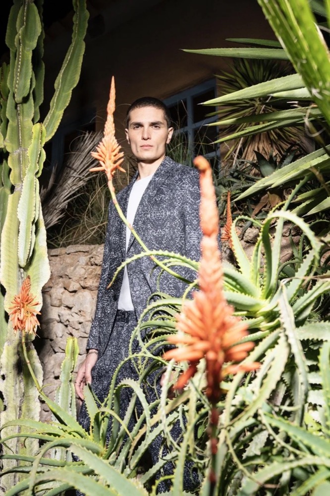 Model im karierten Blazer nachts zwischen Aloeblüten, Drykorn-Kampagne FS/SS 24 Teil II auf Mallorca