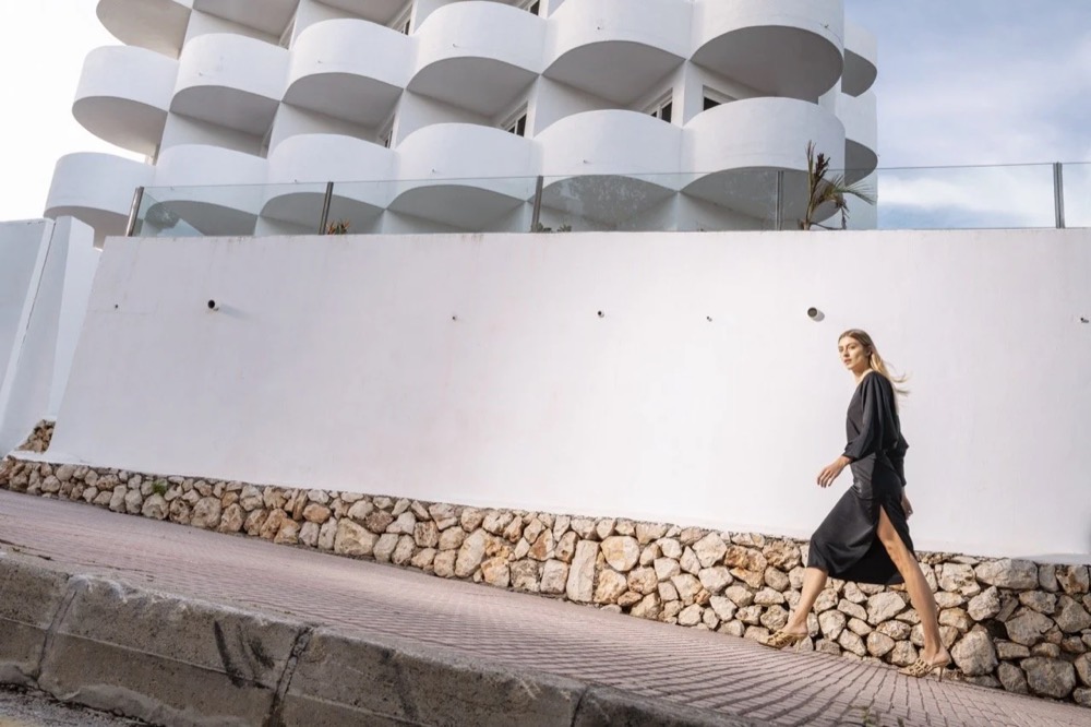 Model geht an einer weißen Hotelmauer am Meer entlang, Drykorn-Kampagne FS/SS 24 Teil II auf Mallorca