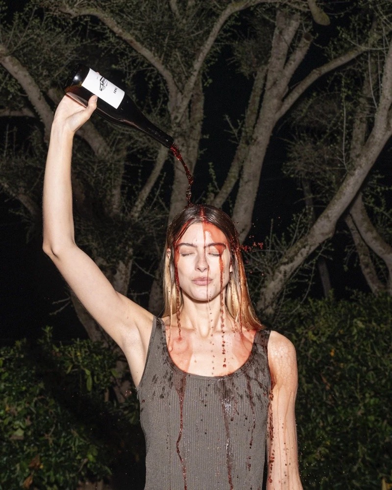 Model hebt in einem dunklen Garten den Arm, Drykorn-Kampagne FS/SS 24 Teil II auf Mallorca