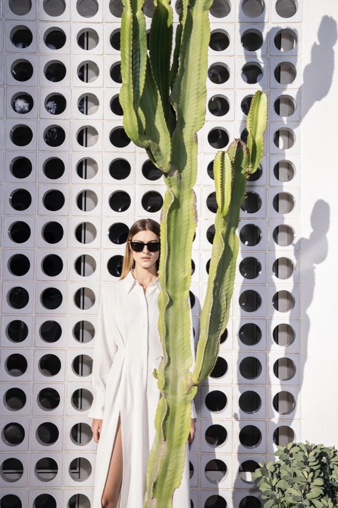 Model mit Sonnenbrille zwischen Kakteen und einer durchbrochenen Mauer, Drykorn-Kampagne FS/SS 24 Teil II auf Mallorca