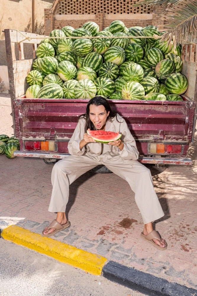 Model isst Wassermelone auf einem Lastwagen voller Melonen, Drykorn-Kampagne FS/SS 24 in Tozeur, Tunesien
