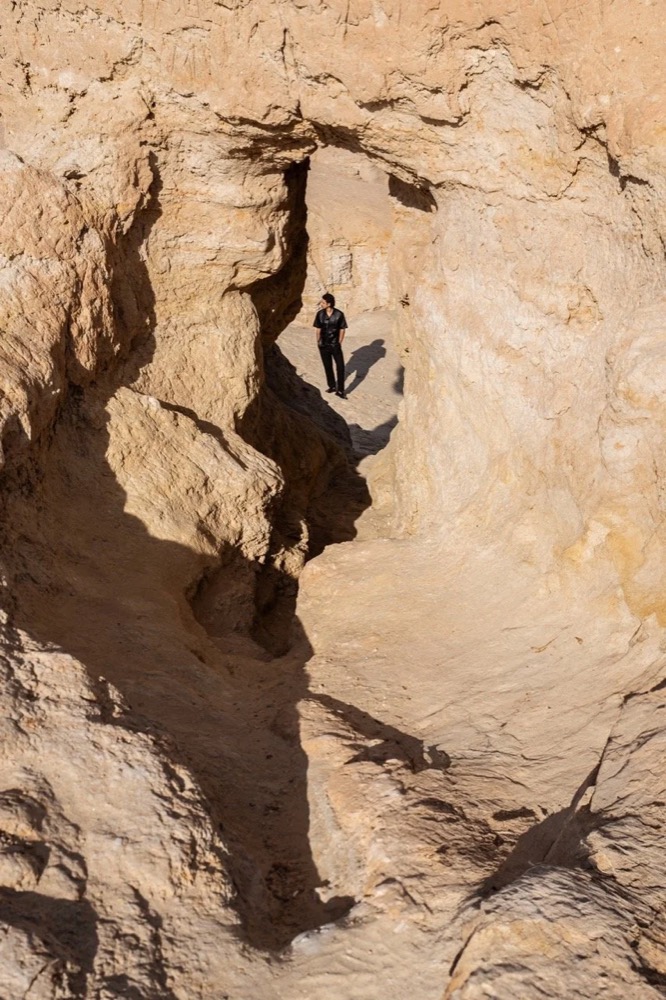Model in einer Sandsteinschlucht, von oben, Drykorn-Kampagne FS/SS 24 in Tozeur, Tunesien