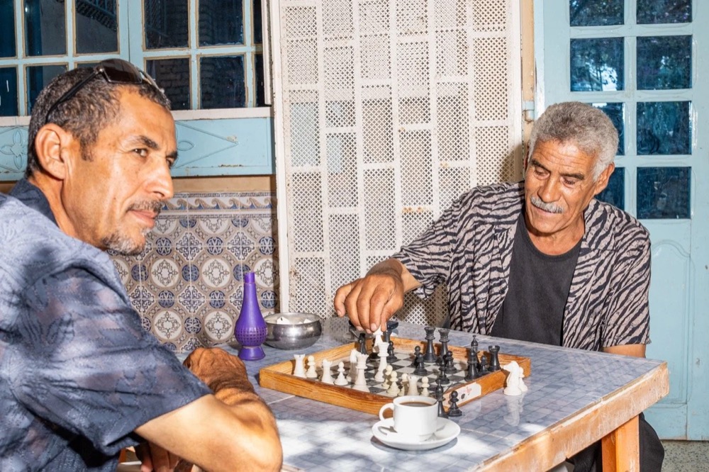 Zwei ältere Männer spielen Schach in einem Café, Drykorn-Kampagne FS/SS 24 in Tozeur, Tunesien