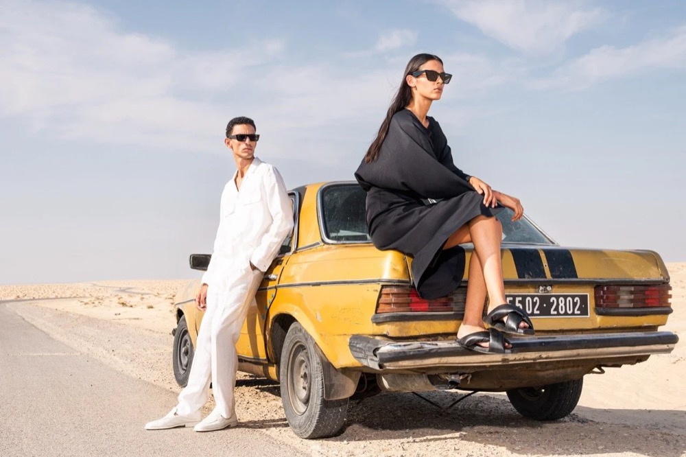Zwei Models auf und neben einem gelben Oldtimer, Drykorn-Kampagne FS/SS 24 in Tozeur, Tunesien