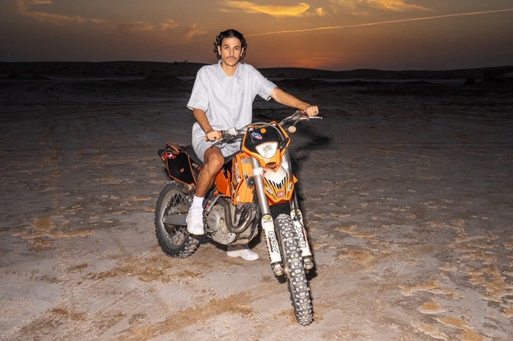 Model auf einem Motorrad in der Wüste bei Sonnenuntergang, Drykorn-Kampagne FS/SS 24 in Tozeur, Tunesien