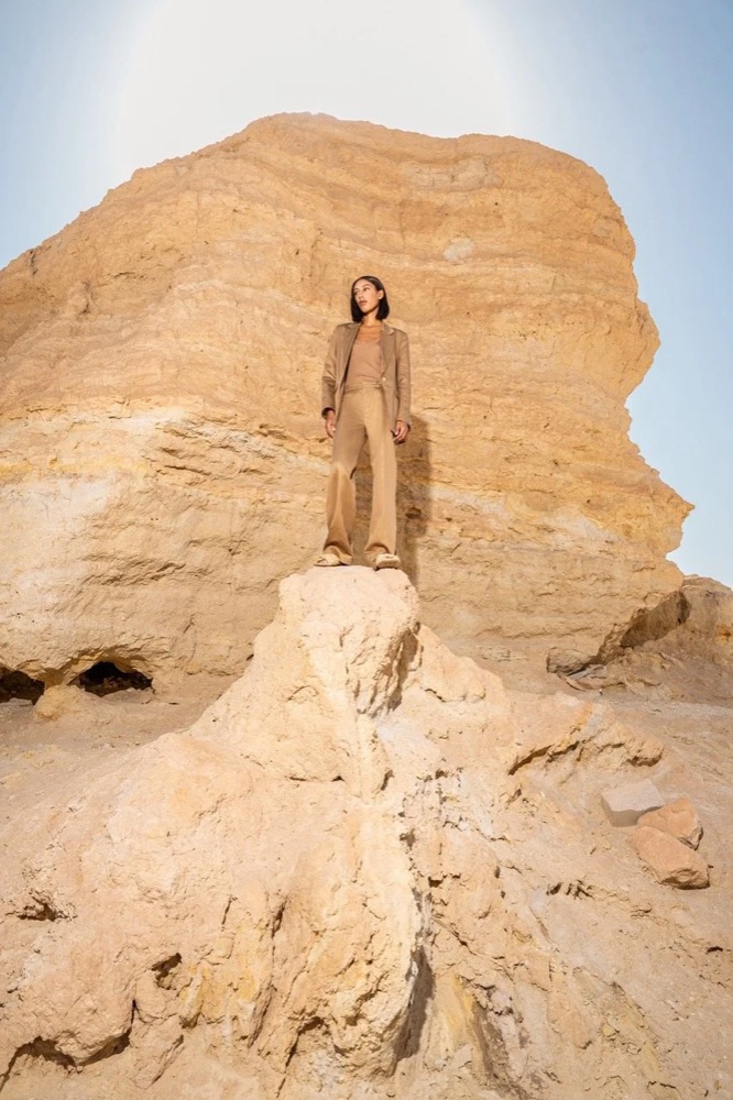 Model steht auf einem großen Sandsteinfelsen, Drykorn-Kampagne FS/SS 24 in Tozeur, Tunesien