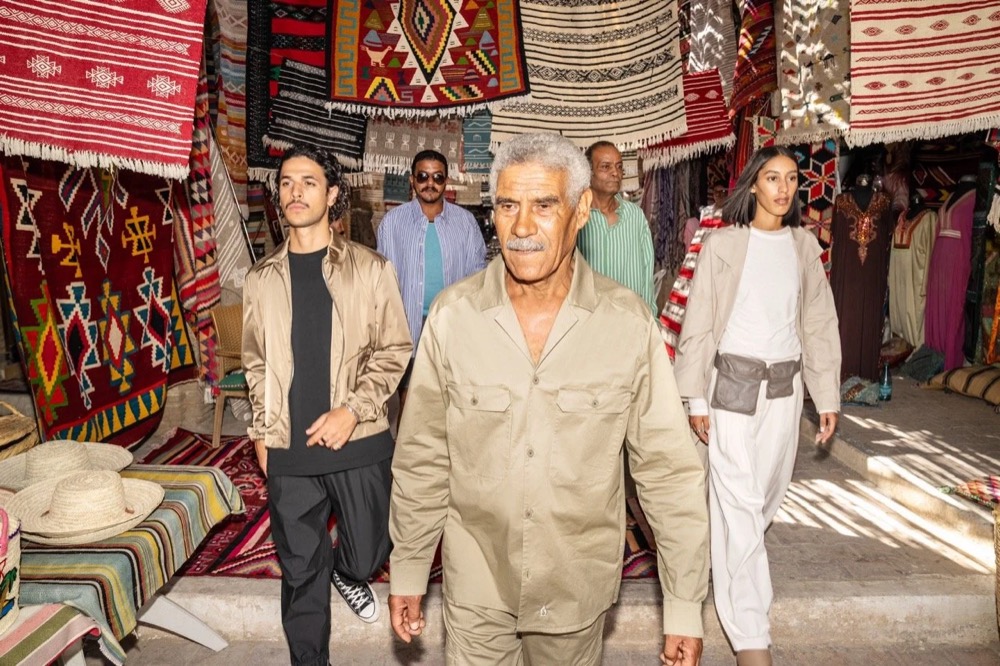 Models mit einem Einheimischen auf einem Teppichmarkt, Drykorn-Kampagne FS/SS 24 in Tozeur, Tunesien