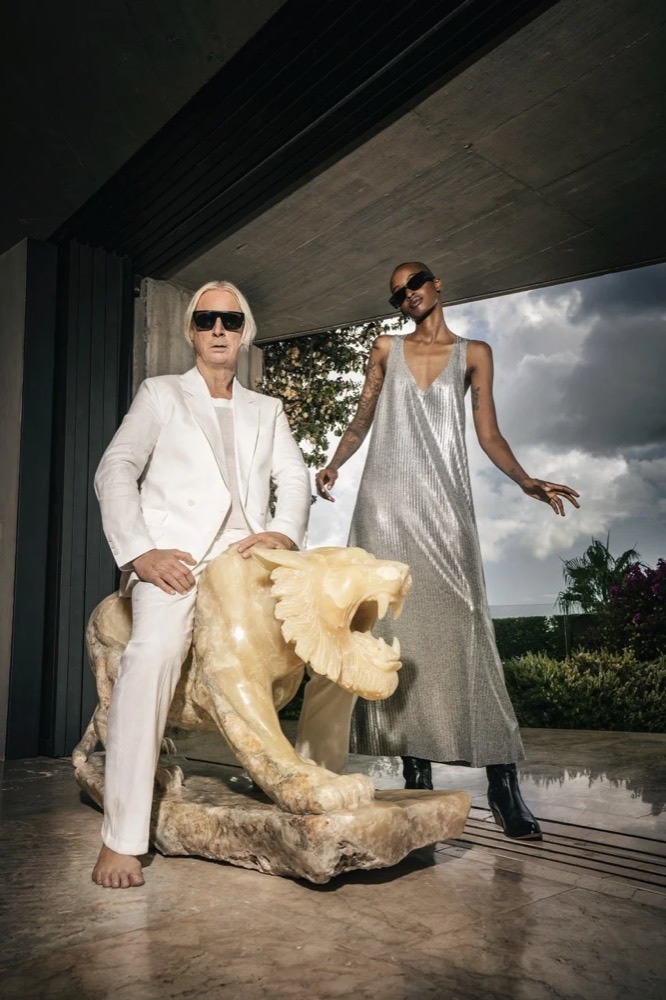 Zwei Models in Weiß und Silber neben einer Löwenskulptur, Drykorn-Kampagne FS/SS25 auf Ibiza