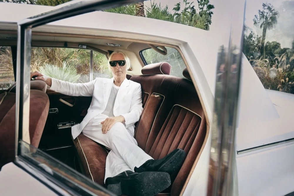 Model in weißem Anzug in einem Oldtimer-Cabrio, Drykorn-Kampagne FS/SS25 auf Ibiza