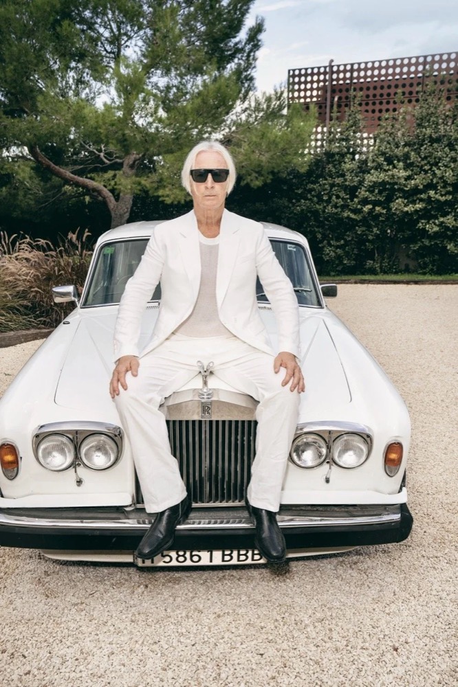 Model in weißem Anzug auf der Motorhaube eines weißen Rolls-Royce, Drykorn-Kampagne FS/SS25 auf Ibiza