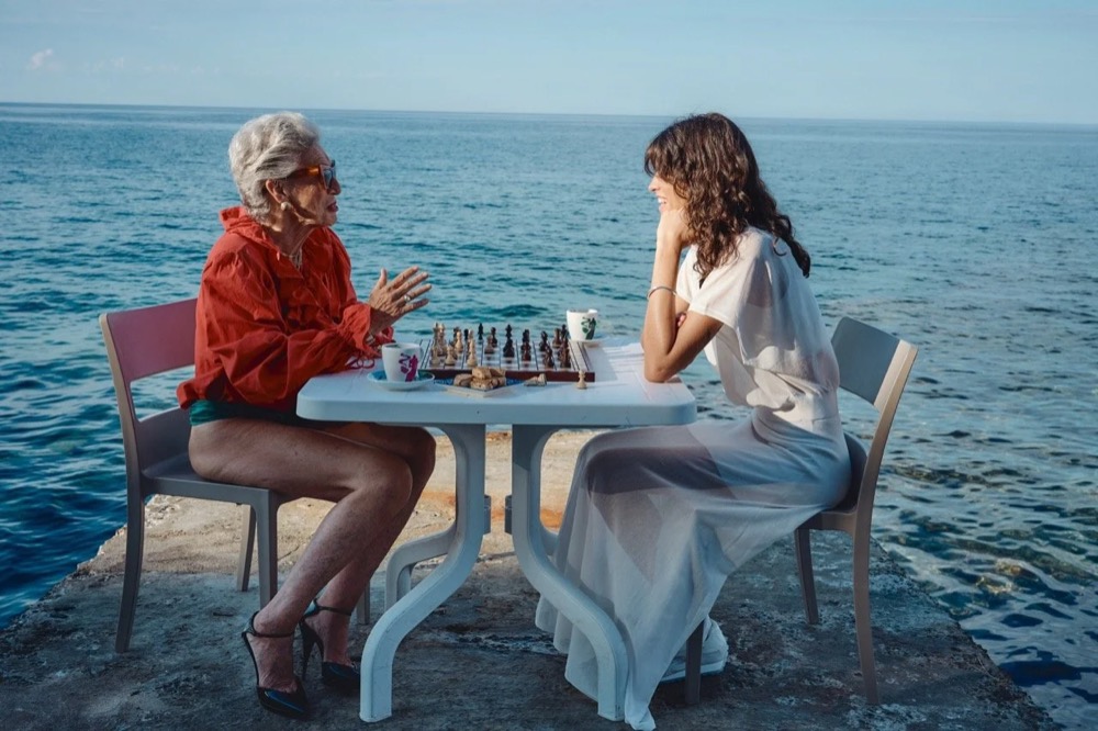 Zwei Models an einem Tisch, der im Meer aufgebaut ist, Drykorn-Kampagne FS/SS26 in Genua