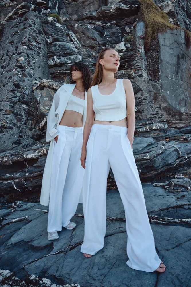 Zwei Models in Weiß auf Küstenfelsen, Drykorn-Kampagne FS/SS26 in Genua