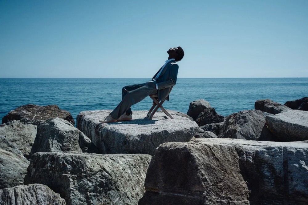 Model springt zwischen Felsen am Meer, Drykorn-Kampagne FS/SS26 in Genua