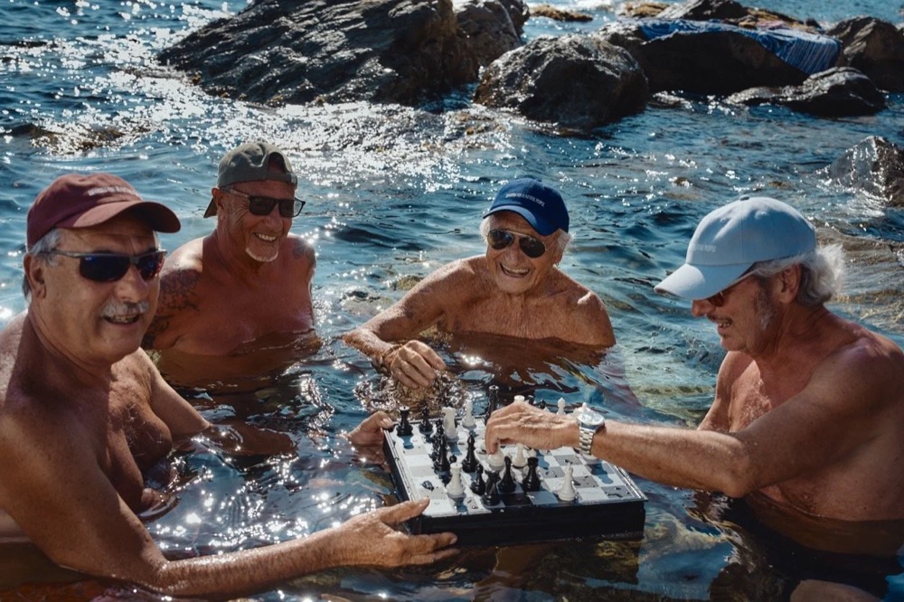 Ältere Männer spielen Schach im Wasser, Totale, Drykorn-Kampagne FS/SS26 in Genua