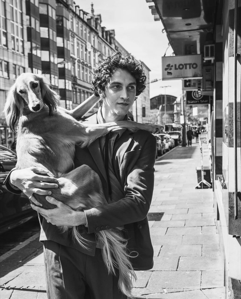 Schwarzweißaufnahme eines Models, das einen Hund trägt, Drykorn-Kampagne HW/AW 2021 in Frankfurt