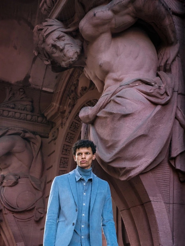 Model im blauen Anzug vor einer verzierten, geschnitzten Fassade, Drykorn-Kampagne HW/AW 2021 in Frankfurt