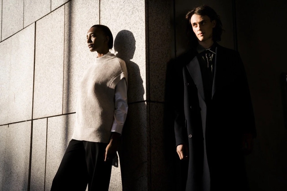 Zwei Models in Licht und Schatten vor einer weißen Wand, Drykorn-Kampagne HW/AW 2021 in Frankfurt