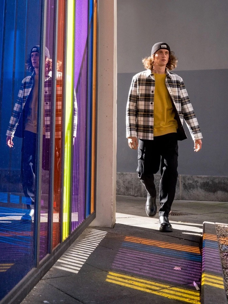Model in karierter Jacke neben buntem Glas, Drykorn-Kampagne HW/AW 2021 in Frankfurt