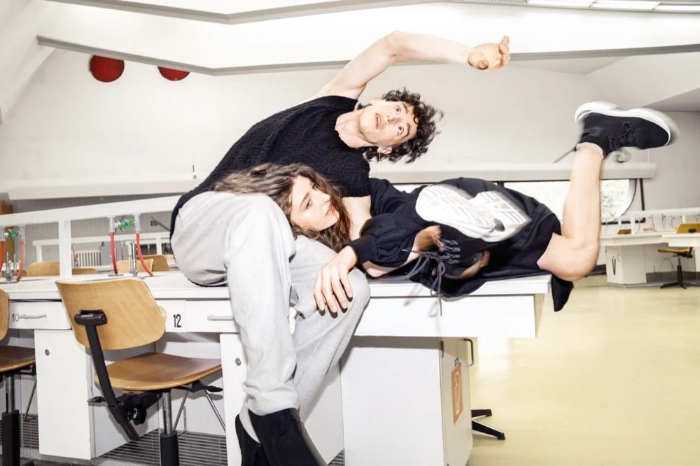 Zwei Models posieren auf Schreibtischen in einem Büro, Drykorn-Kampagne HW/AW 22