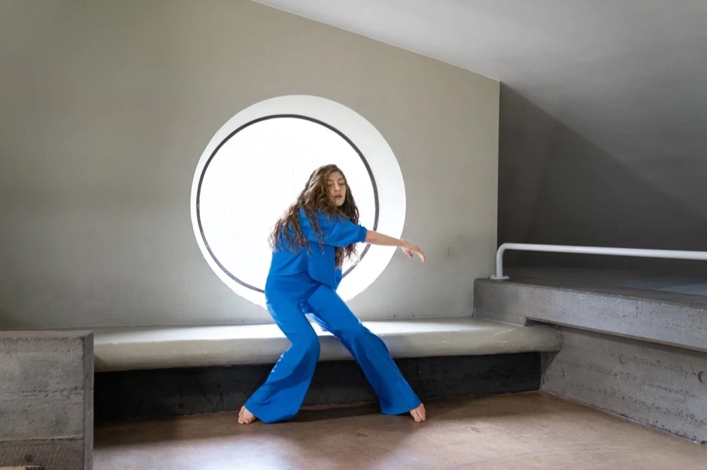 Model in Blau vor einem runden Fenster, Drykorn-Kampagne HW/AW 22