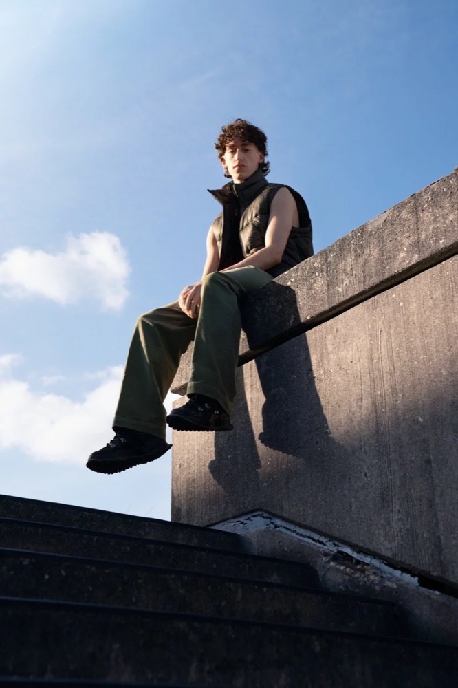 Model sitzt vor blauem Himmel auf einer Betonmauer, Drykorn-Kampagne HW/AW 22