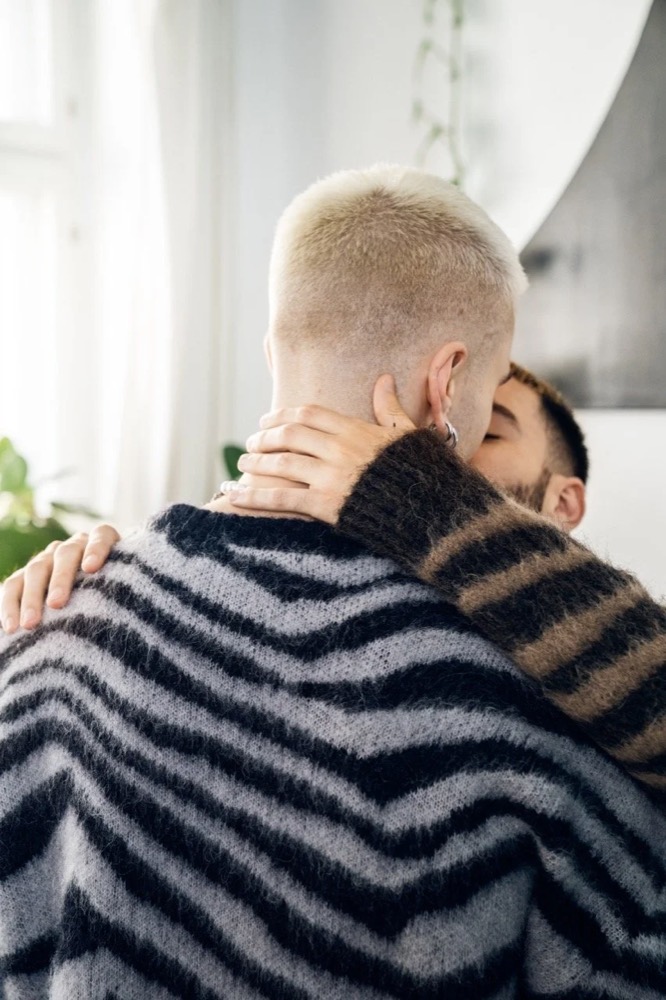 Zwei Männer umarmen sich, einer im gestreiften Strickpullover, Drykorn-Kampagne HW/AW 22