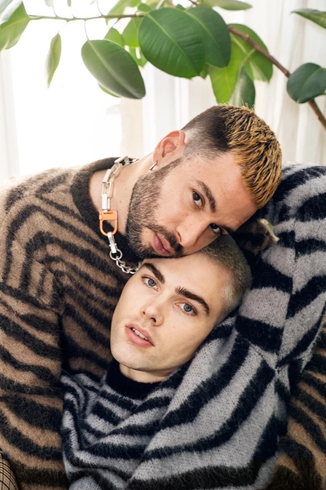Zwei Männer in Strick kuscheln unter einer Pflanze, Drykorn-Kampagne HW/AW 22