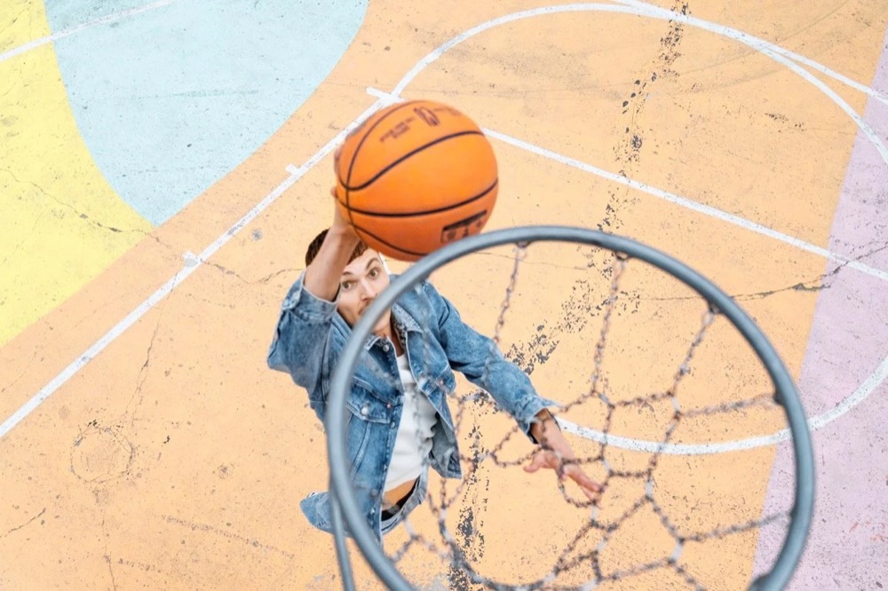 Model mit Basketball unter einem Korb, von oben, Drykorn-Kampagne HW/AW 22
