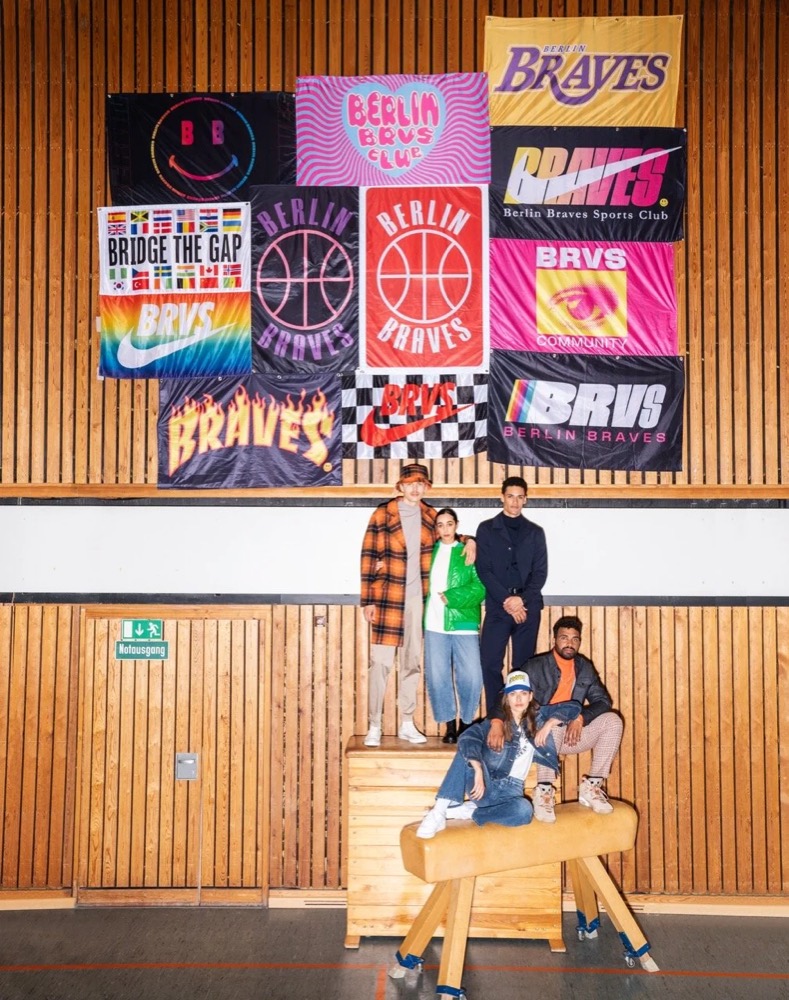 Gruppe von Models vor einer Wand voller Sportwimpel, Drykorn-Kampagne HW/AW 22
