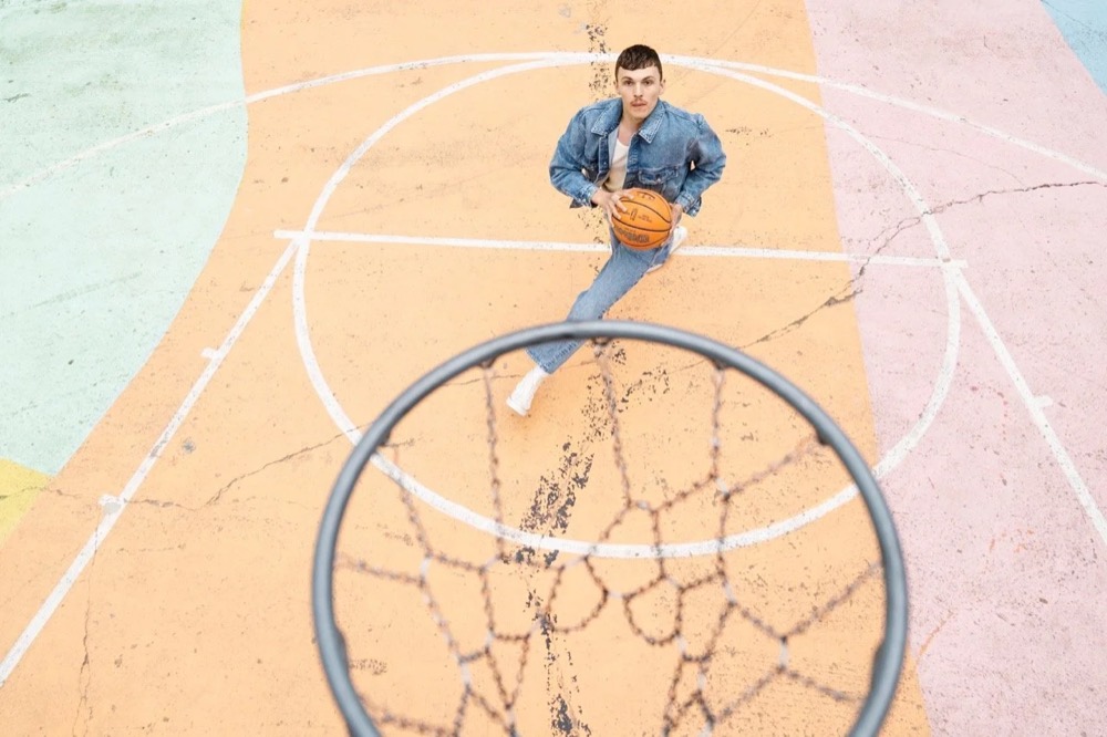 Model liegt unter einem Basketballkorb, von oben, Drykorn-Kampagne HW/AW 22