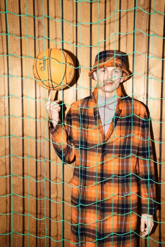Model im karierten Mantel dreht hinter einem Zaun einen Basketball, Drykorn-Kampagne HW/AW 22
