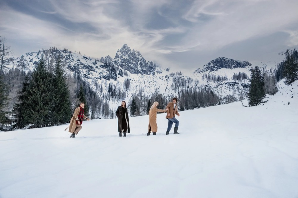 Gruppe von Models geht durch den Schnee, dahinter Berge, Drykorn-Kampagne HW/AW 23 in Bad Gastein