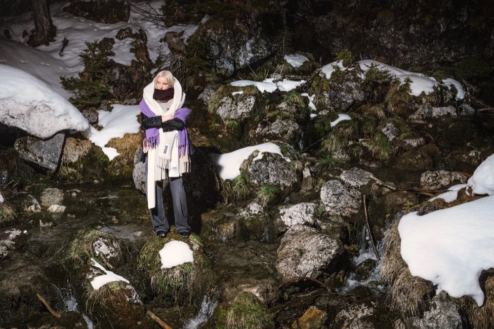 Model zwischen verschneiten Felsen, von oben, Drykorn-Kampagne HW/AW 23 in Bad Gastein