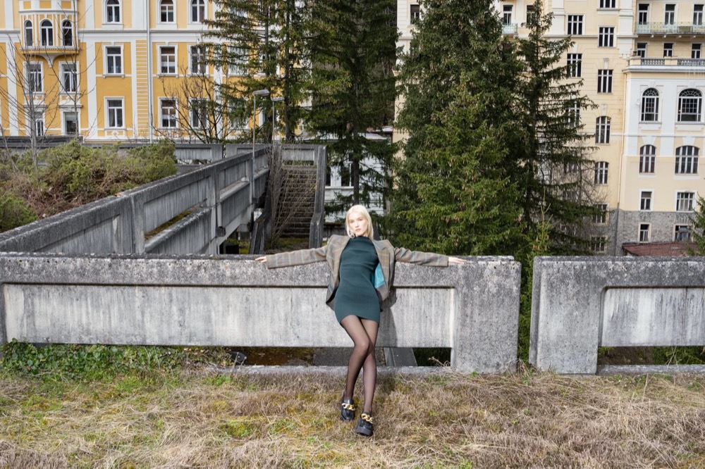 Model geht eine Bergstraße entlang, Drykorn-Kampagne HW/AW 23 in Bad Gastein
